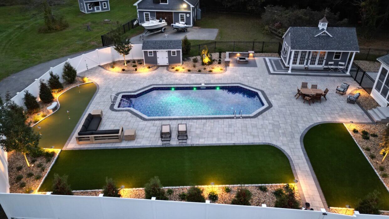 Backyard oasis with a custom in-ground pool, putting green, lounge seating, outdoor fire pit, and decorative landscape lighting