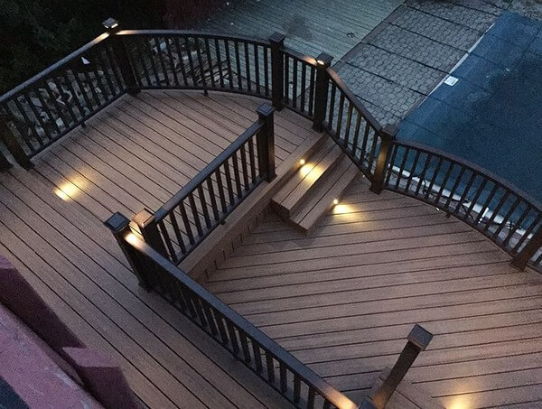 Multi-level composite deck with integrated lighting and curved railings at dusk